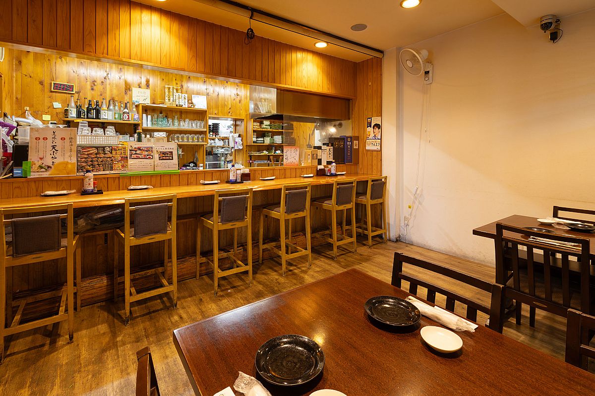 カウンターとテーブル席の和風居酒屋風の店内。奥には個室座敷も